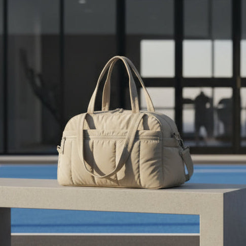 Woman sitting outdoors with a beige duffel bag, holding a water bottle, with text 'Ultra Lightweight for Carrying Comfort'.