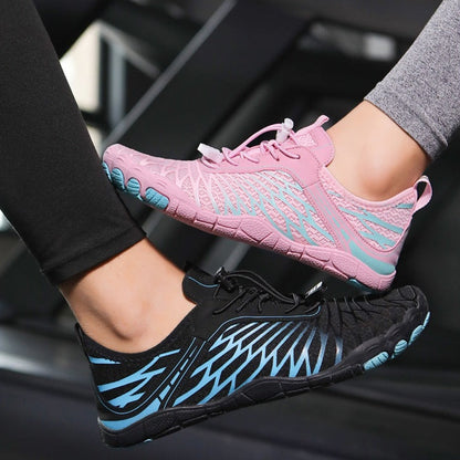 Pink and black athletic shoes with blue accents worn by a person.