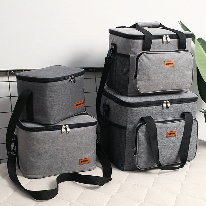 Set of gray and black insulated bags on a tiled floor.