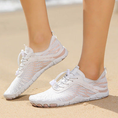 White sneakers worn on a beach with ocean view