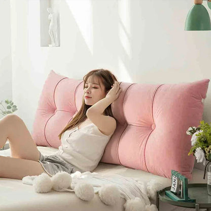 Woman relaxing on a bed with a large pink backrest pillow in a bright bedroom