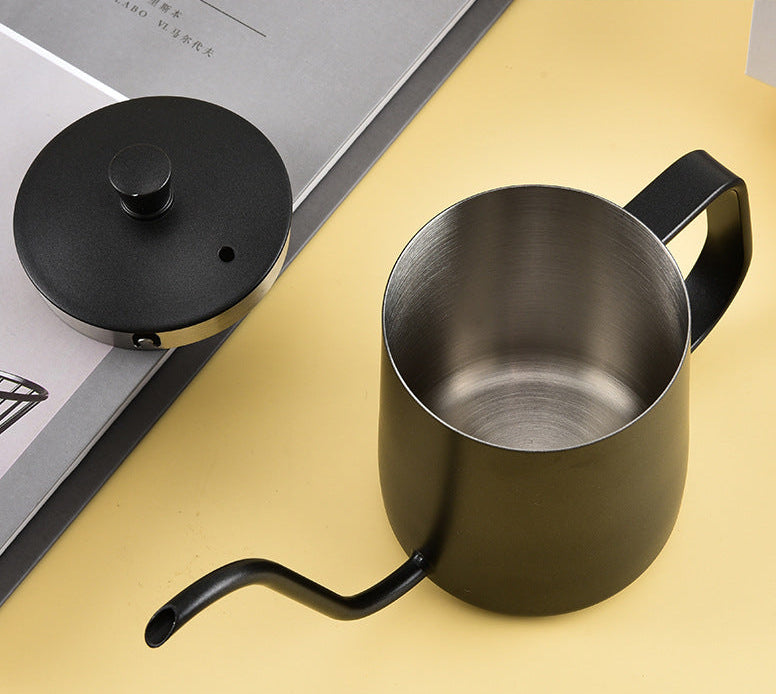 Black metal kettle with a long spout on a yellow surface