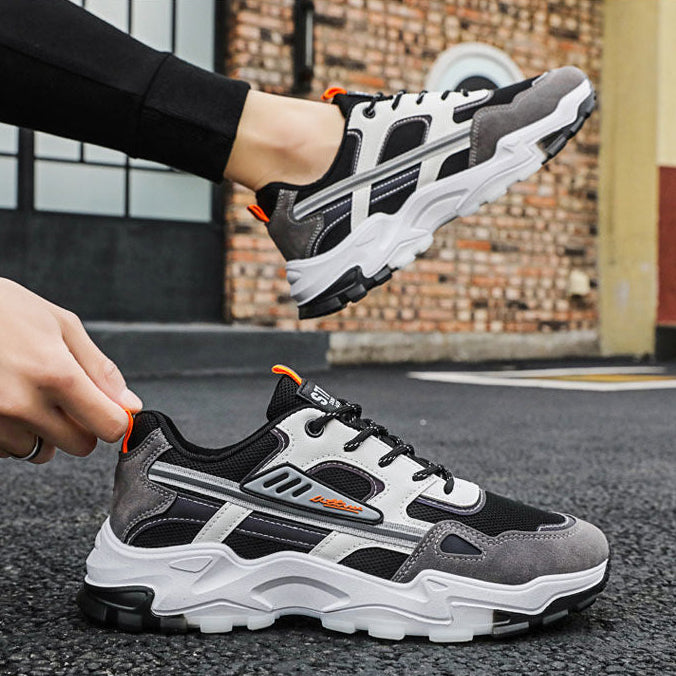 Gray and black sneakers with orange accents on a street background