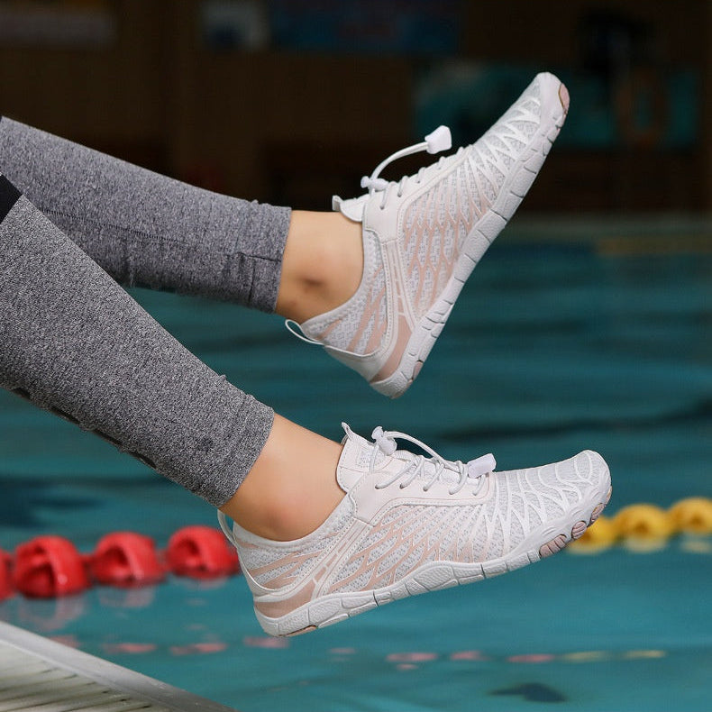 White sneakers worn by a person with gray leggings, with a pool in the background.
