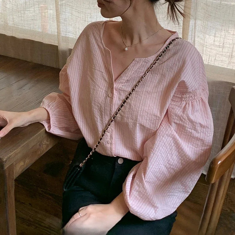 Woman in a loose light pink striped blouse with long sleeves, casual chic fashion