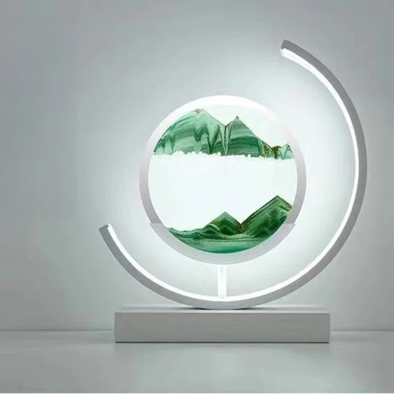 Modern circular LED sand art lamp with green mountains design on a white base