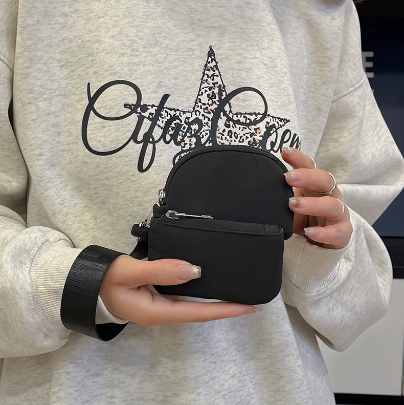Person holding a black circular pouch with a light gray sweatshirt featuring a star design.