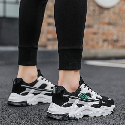 Black and white sneakers worn with black pants on a blurred outdoor background