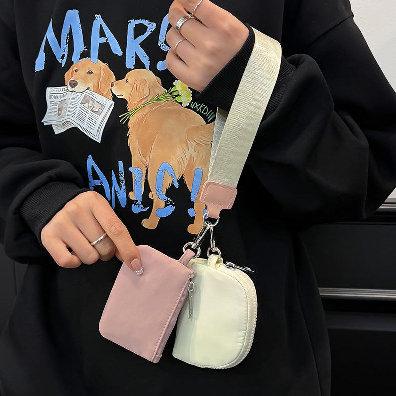 Person holding two small pouches with a black hoodie featuring dog graphics.