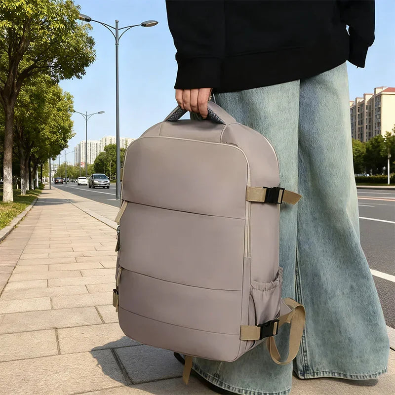 Person holding a stylish beige backpack on a city sidewalk, casual street fashion
