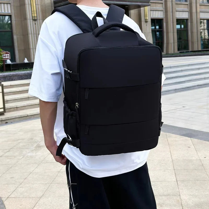 Man wearing large black backpack outdoors, modern urban setting, casual travel gear