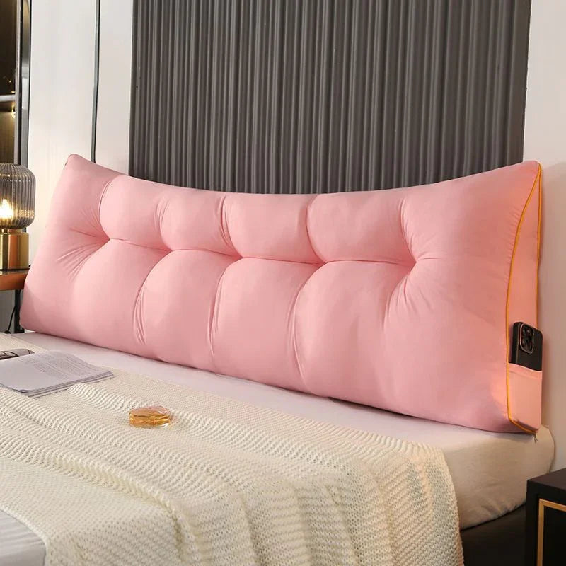 Large pink tufted headboard pillow on a bed with cream knit blanket, modern bedroom decor