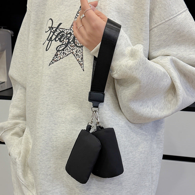 Person wearing a light gray sweatshirt with a star design, holding a black crossbody bag.