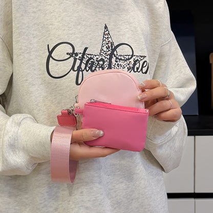 Person holding a pink pouch with a white sweatshirt featuring black text and graphics.