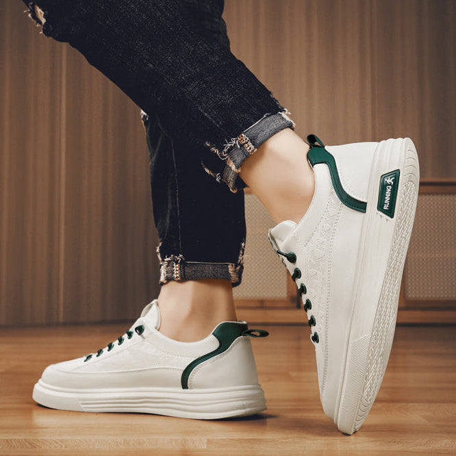 White sneakers with green accents worn by a person on a wooden floor.