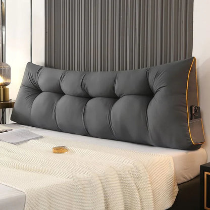 Large gray tufted headboard pillow on a modern bed with a white knit blanket