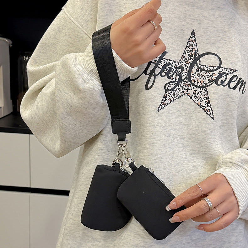 Person holding two black pouches with a white sweatshirt featuring a star design.