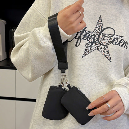 Person holding two black pouches with a white sweatshirt featuring a star design.