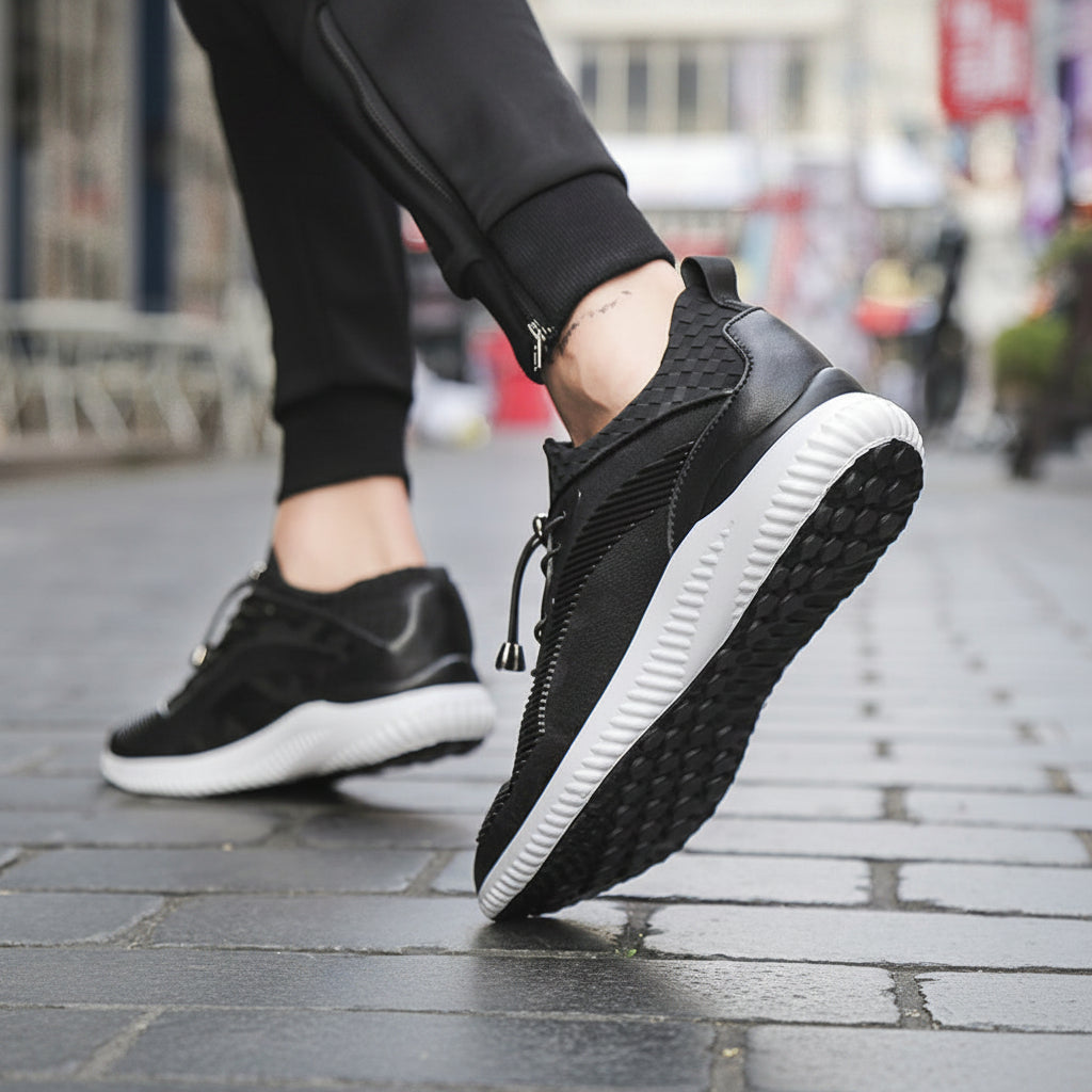 Black sneakers with white soles worn on a blurred street background