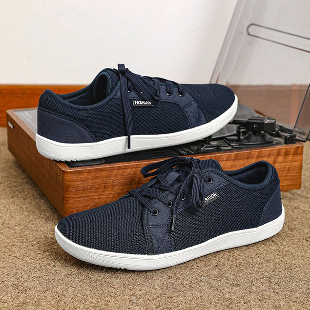 Navy blue sneakers with white soles on a wooden surface.