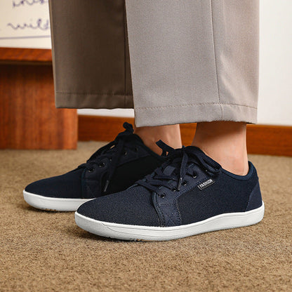 Navy blue sneakers worn with beige pants on a carpeted floor.